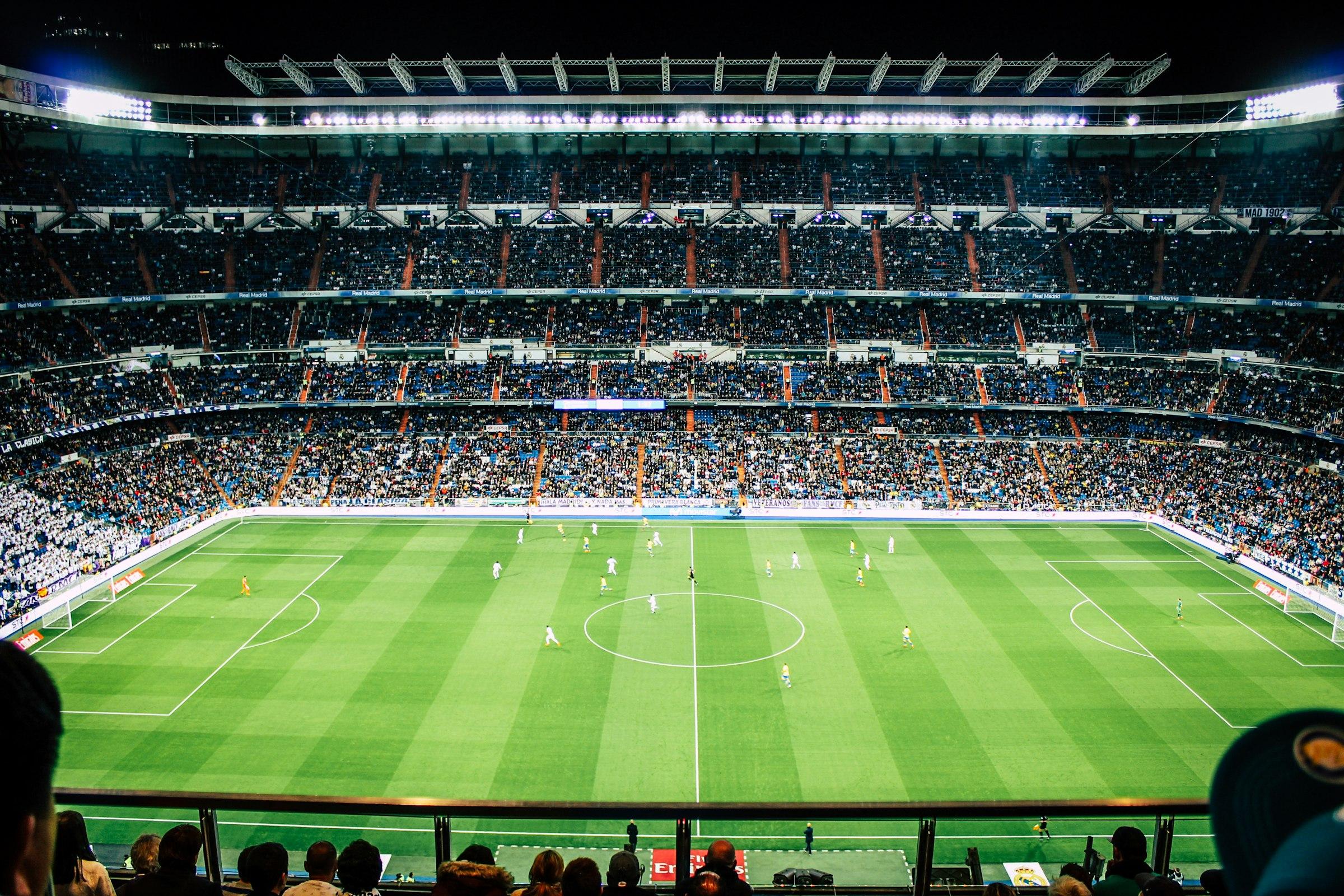 A packed soccer stadium under evening floodlights